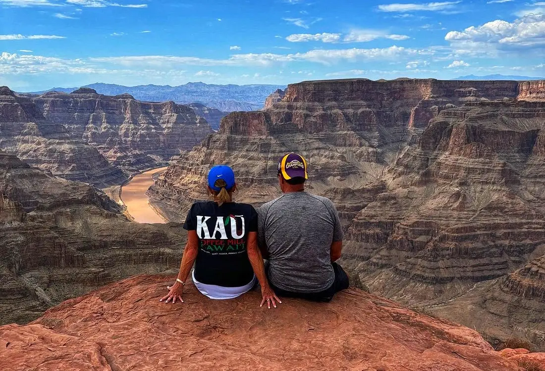 A guy and a girl look down from above at the Grand Canyon and the river