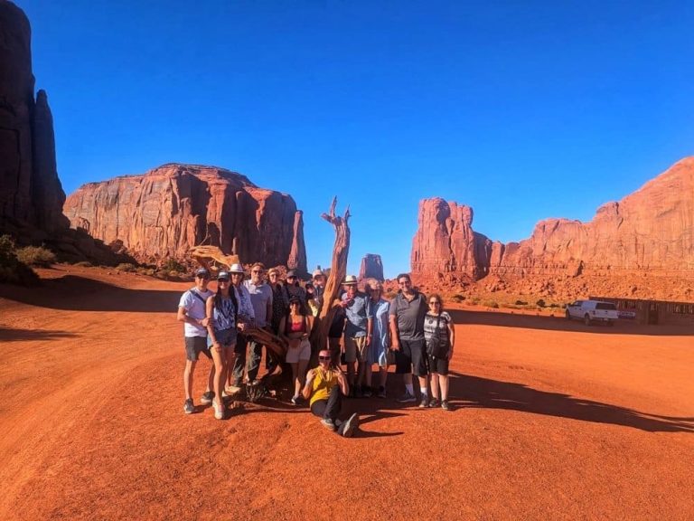 A group of tourists pose near the Monument Valley